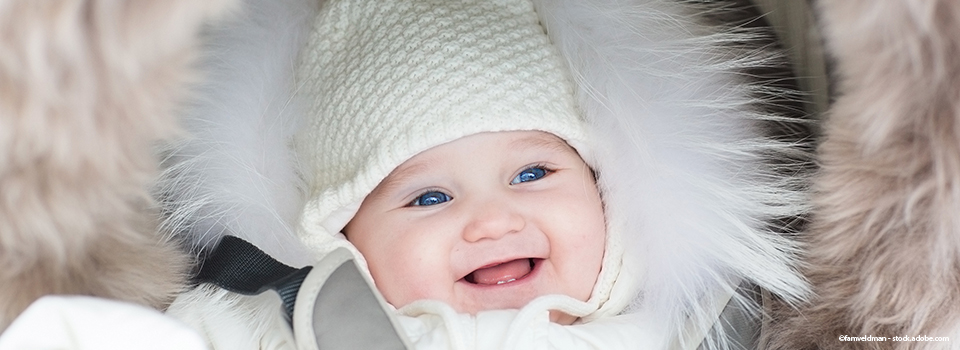 bébé dans une poussette habillé pour l'hiver dans une chancelière 